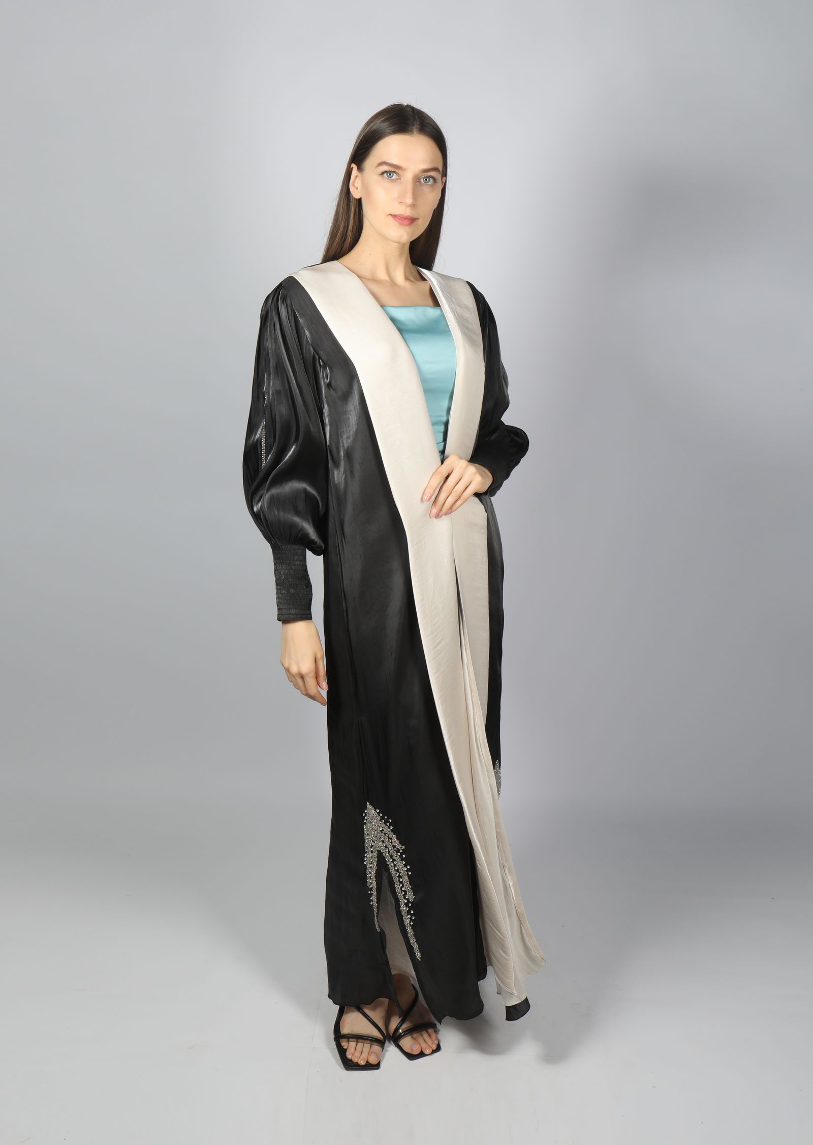 Model wearing a black and cream abaya in a studio setting